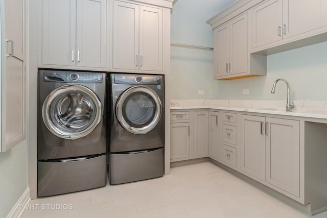 clothes washing area with washer and dryer, cabinets, and sink