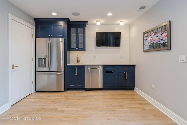 kitchen featuring blue cabinets, light wood-type flooring, appliances with stainless steel finishes, and sink