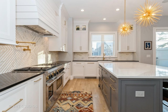 kitchen with a chandelier, double oven range, decorative light fixtures, white cabinetry, and dark stone counters