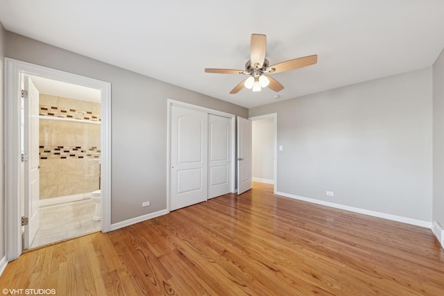 unfurnished bedroom featuring ceiling fan, a closet, light wood-type flooring, and ensuite bath