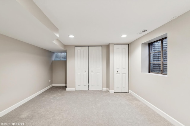 unfurnished bedroom with light colored carpet and two closets