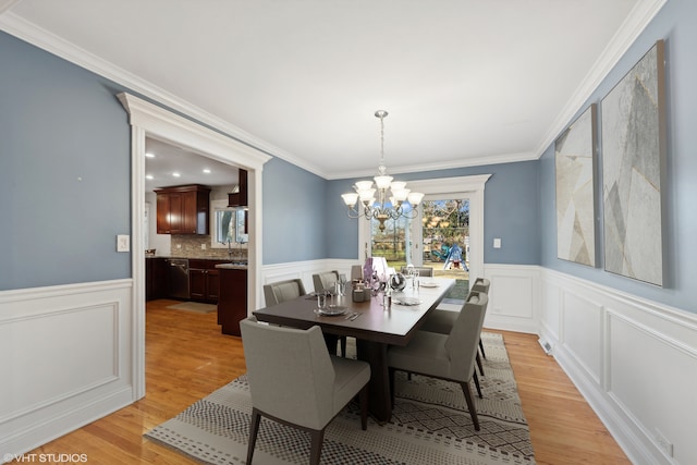 dining space with a notable chandelier, light hardwood / wood-style floors, and ornamental molding