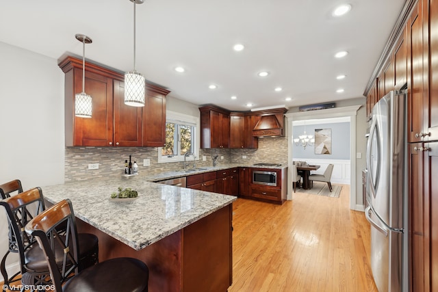 kitchen featuring a kitchen breakfast bar, kitchen peninsula, hanging light fixtures, and appliances with stainless steel finishes