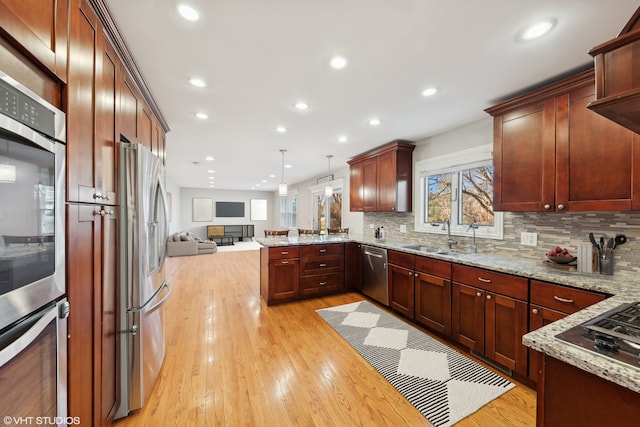 kitchen with decorative backsplash, light stone counters, stainless steel appliances, sink, and pendant lighting