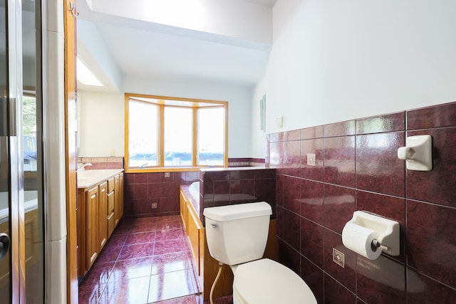 bathroom with tile patterned floors, vanity, toilet, and tile walls