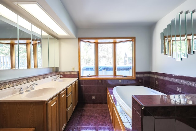 bathroom featuring tile patterned floors, vanity, a tub to relax in, and tile walls