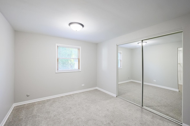 unfurnished bedroom featuring light carpet and a closet