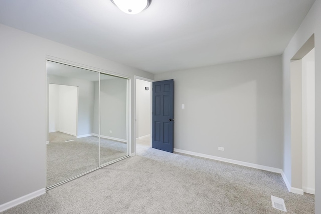 unfurnished bedroom with a closet and light colored carpet