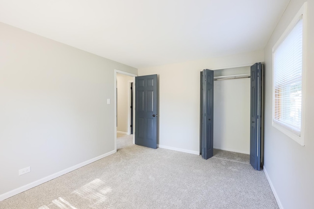 unfurnished bedroom with light carpet and a closet