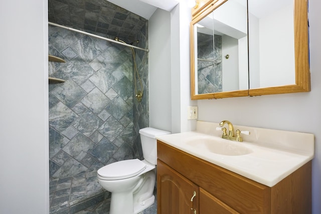 bathroom with vanity, toilet, and tiled shower