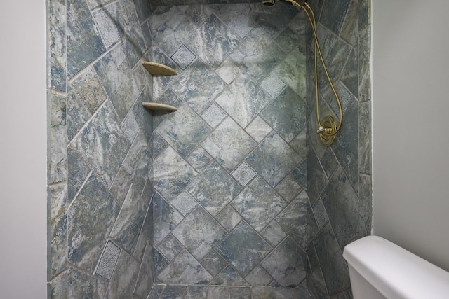 bathroom featuring a tile shower and toilet