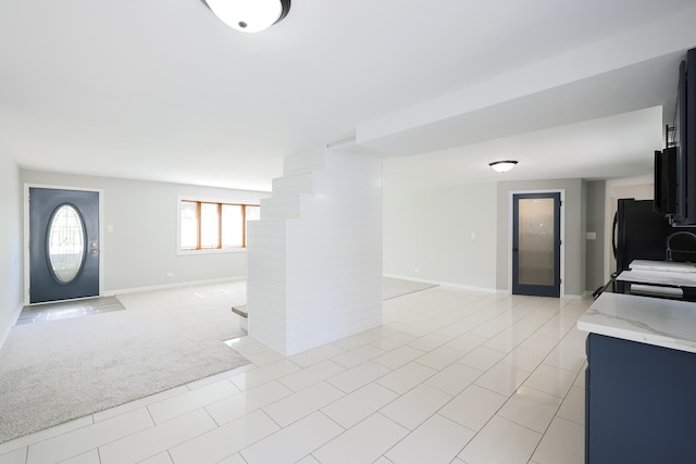 kitchen with black fridge and light colored carpet