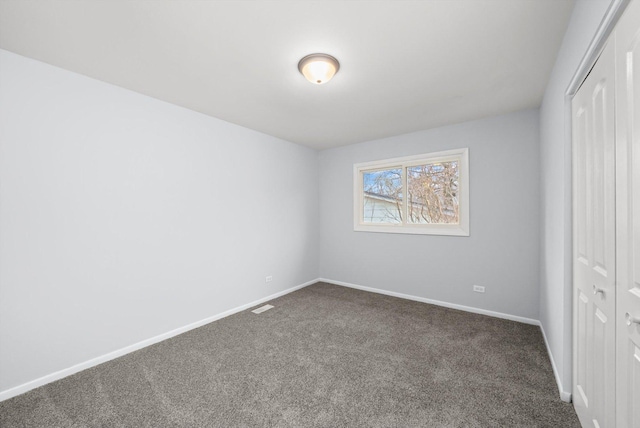 unfurnished bedroom with dark carpet and a closet