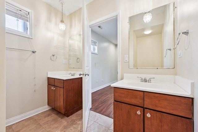 full bath featuring a sink, tile patterned flooring, baseboards, and two vanities