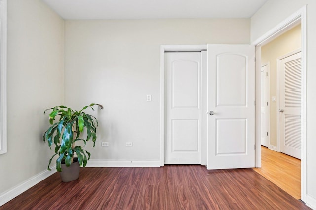 unfurnished bedroom featuring baseboards and dark wood-type flooring