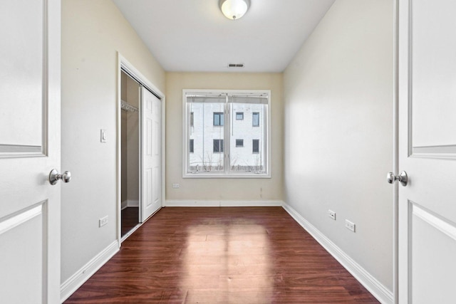 interior space with dark wood-style floors, baseboards, visible vents, and a closet