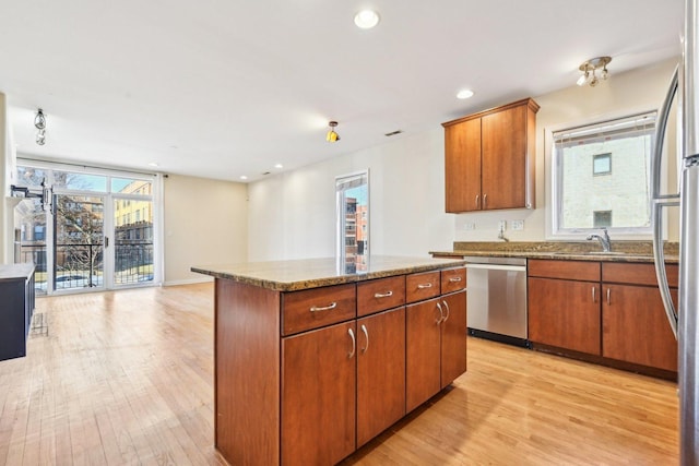 kitchen featuring light wood finished floors, appliances with stainless steel finishes, a healthy amount of sunlight, and a center island