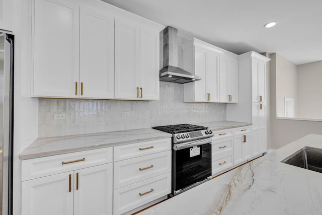 kitchen featuring stainless steel gas stove, wall chimney exhaust hood, white cabinetry, and light stone countertops