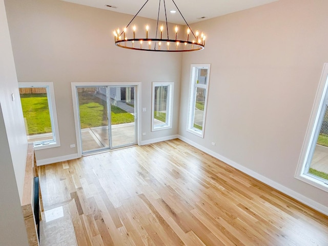 unfurnished dining area featuring baseboards, light wood-style flooring, and a notable chandelier