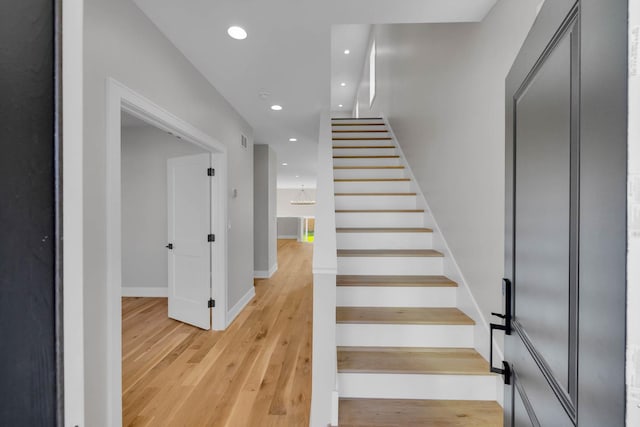 stairs featuring baseboards, wood finished floors, and recessed lighting