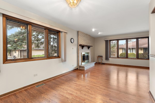 unfurnished living room featuring light hardwood / wood-style flooring and a brick fireplace