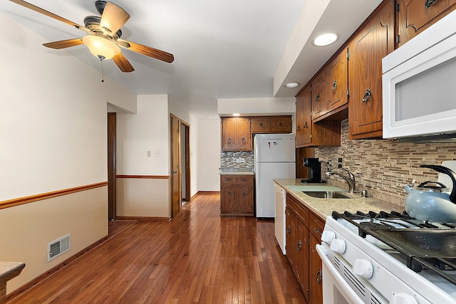 kitchen with white appliances, backsplash, sink, ceiling fan, and dark hardwood / wood-style flooring