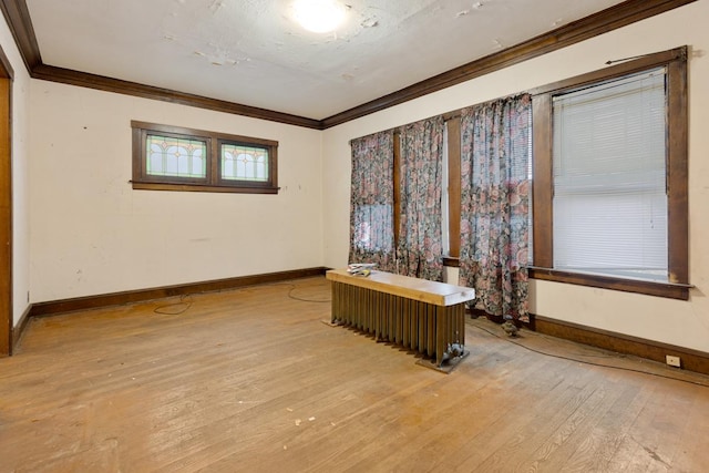 empty room with radiator heating unit, crown molding, and wood-type flooring