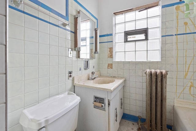 bathroom with radiator heating unit, vanity, toilet, and tile walls