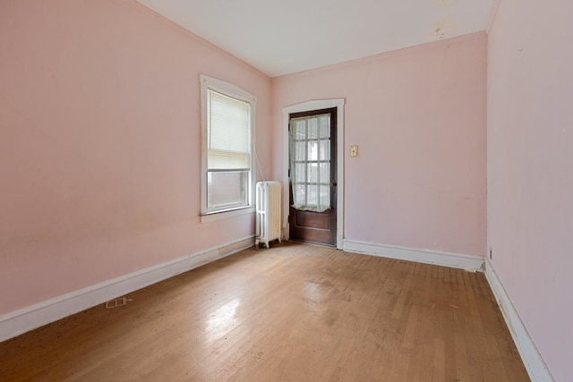 spare room featuring radiator and light hardwood / wood-style flooring