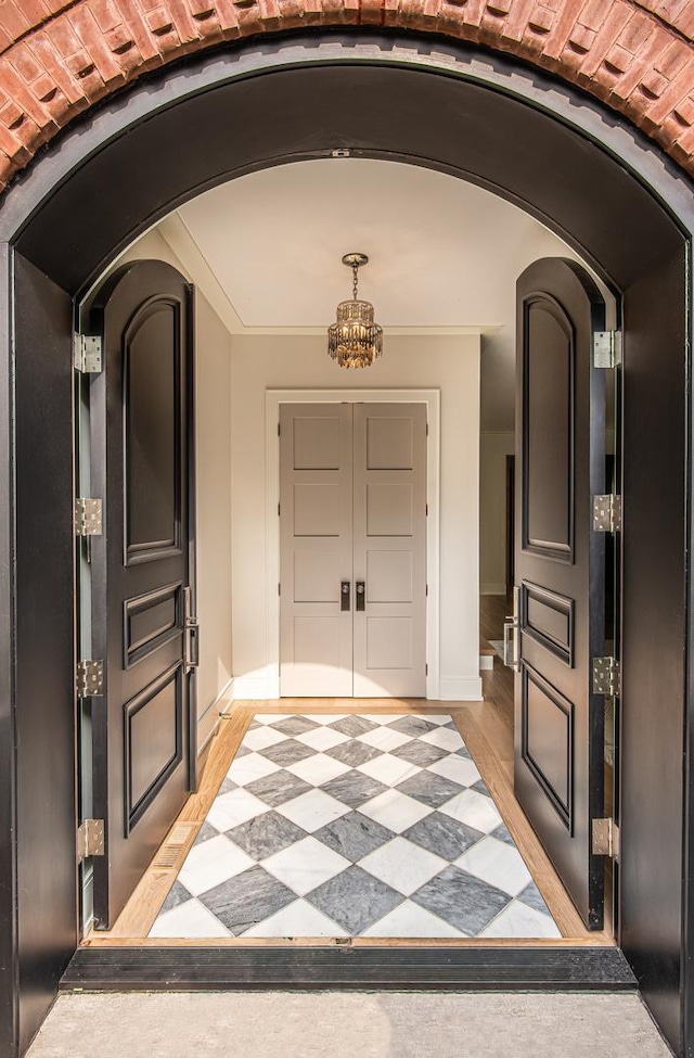 foyer entrance featuring an inviting chandelier, brick ceiling, and light hardwood / wood-style flooring