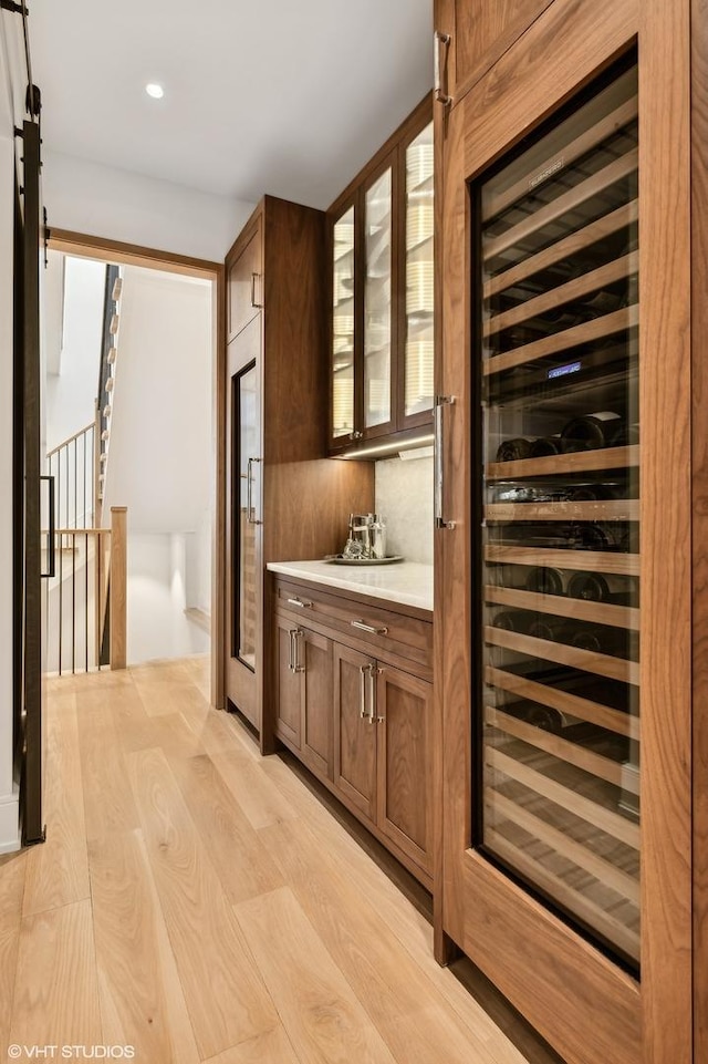 bar featuring a barn door, wine cooler, and light hardwood / wood-style floors