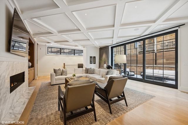 living room with coffered ceiling, a fireplace, beam ceiling, and light wood-type flooring