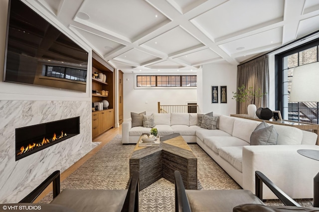 living room with built in features, hardwood / wood-style floors, coffered ceiling, a high end fireplace, and beamed ceiling