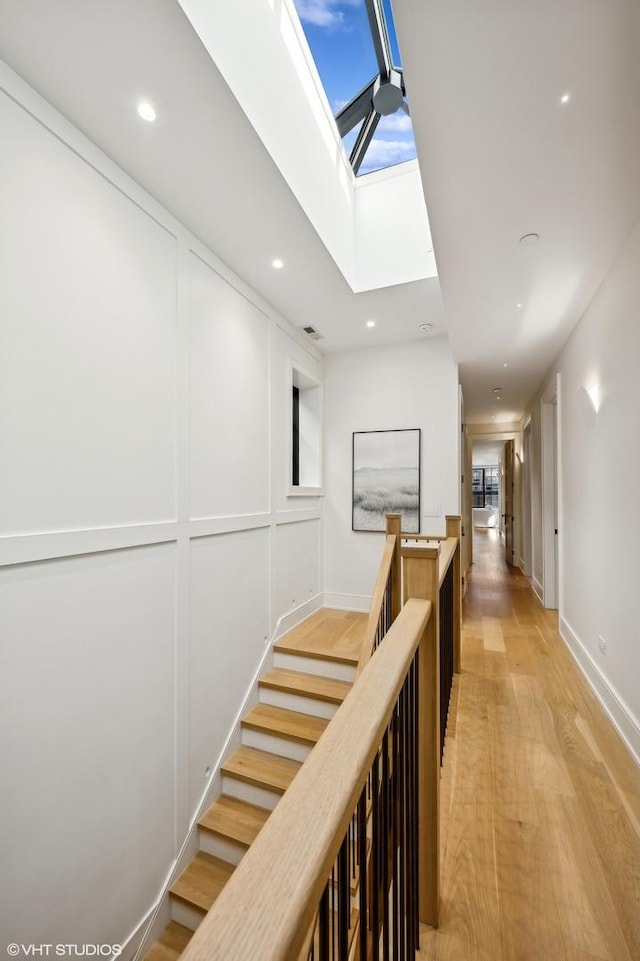 hall with light hardwood / wood-style floors and a skylight