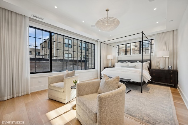 bedroom with a tray ceiling and light hardwood / wood-style flooring