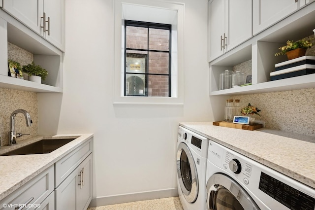 clothes washing area with cabinets, sink, and washing machine and clothes dryer