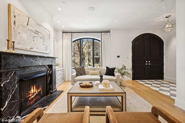 living room featuring ornamental molding, a high end fireplace, and light hardwood / wood-style floors