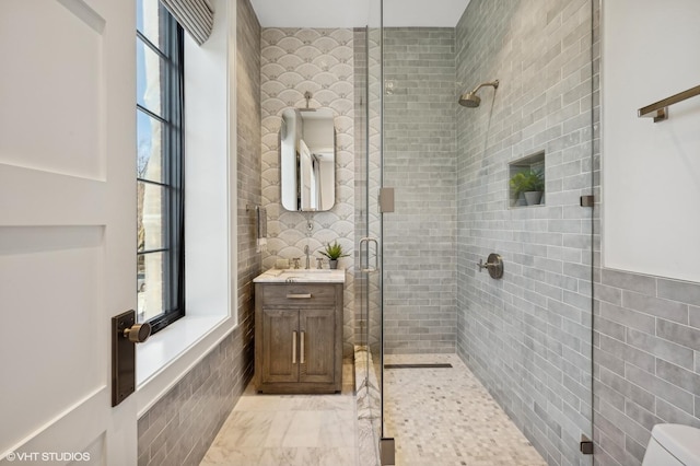 bathroom featuring vanity, toilet, an enclosed shower, and tile walls