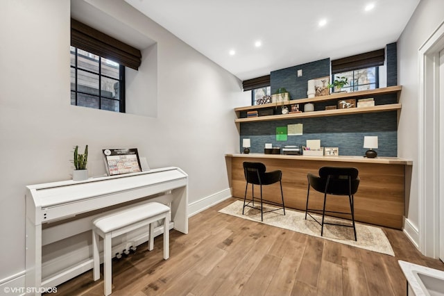 bar with backsplash, wood-type flooring, built in desk, and a wealth of natural light