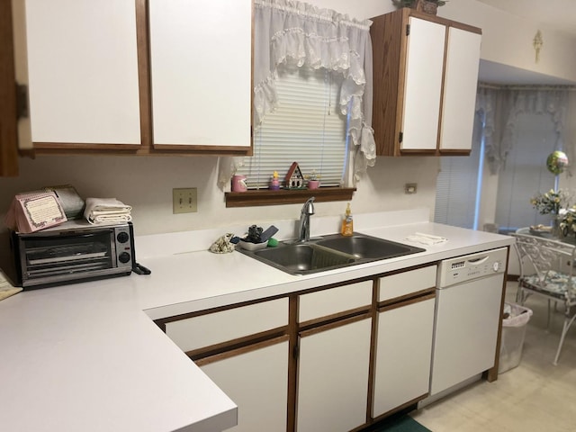 kitchen featuring white dishwasher, white cabinetry, hanging light fixtures, and sink