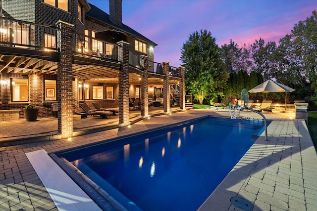 pool at dusk featuring a patio area