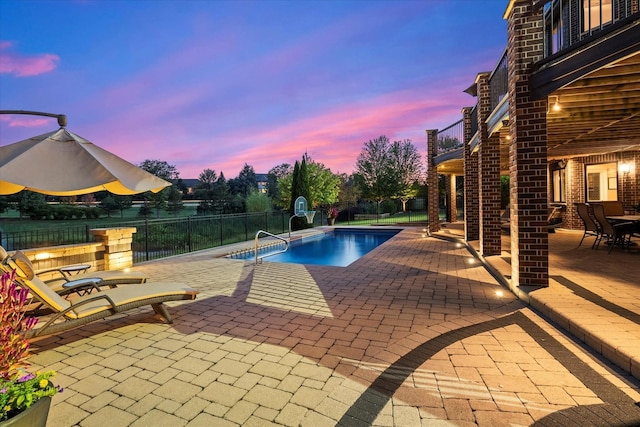 pool at dusk featuring a patio