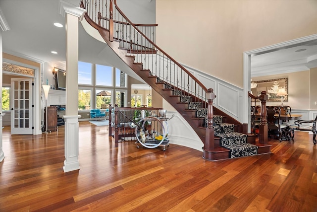 stairs featuring hardwood / wood-style floors, a towering ceiling, and decorative columns