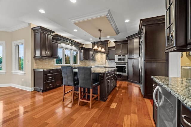 kitchen with beverage cooler, crown molding, a center island, hanging light fixtures, and a breakfast bar area