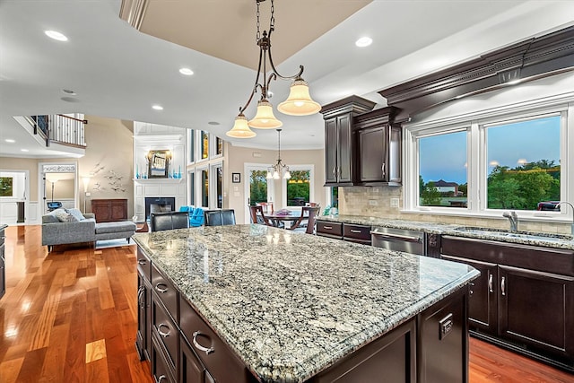 kitchen featuring backsplash, stainless steel dishwasher, crown molding, a kitchen island, and hanging light fixtures