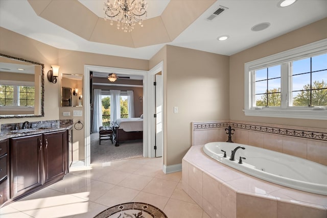 bathroom featuring tile patterned floors, tiled tub, vanity, and a chandelier