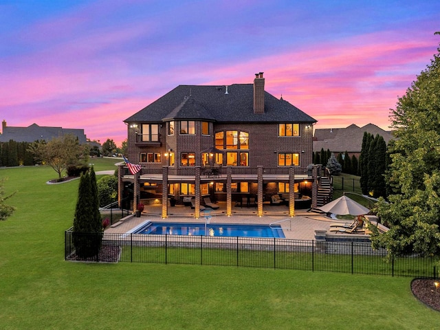 back house at dusk featuring outdoor lounge area, a yard, and a patio area