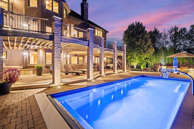 pool at dusk featuring a patio