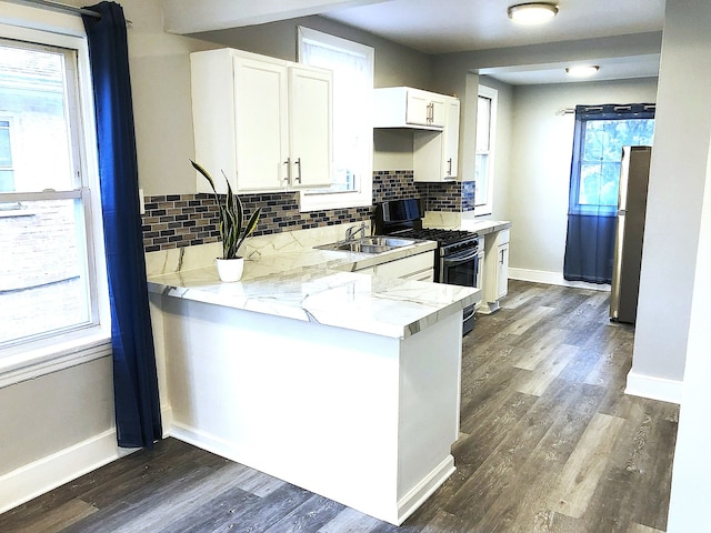 kitchen with tasteful backsplash, gas range, sink, and white cabinets