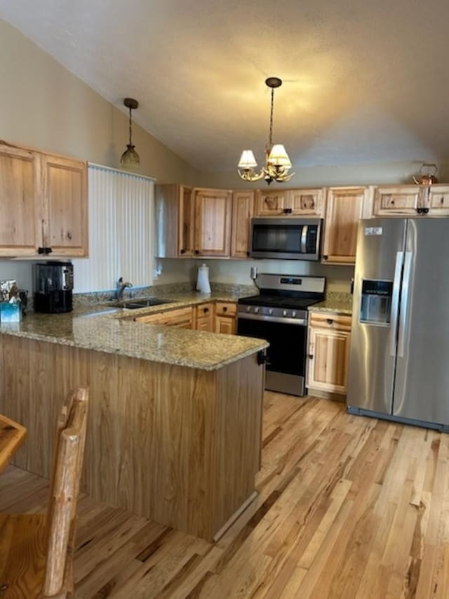 kitchen featuring kitchen peninsula, hanging light fixtures, appliances with stainless steel finishes, and an inviting chandelier